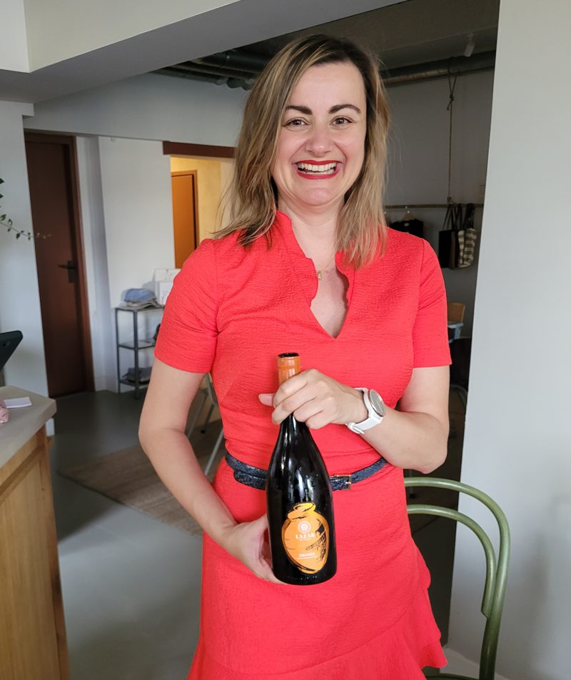Biljana lachend met een fles Macedonische orange wine in haar handen