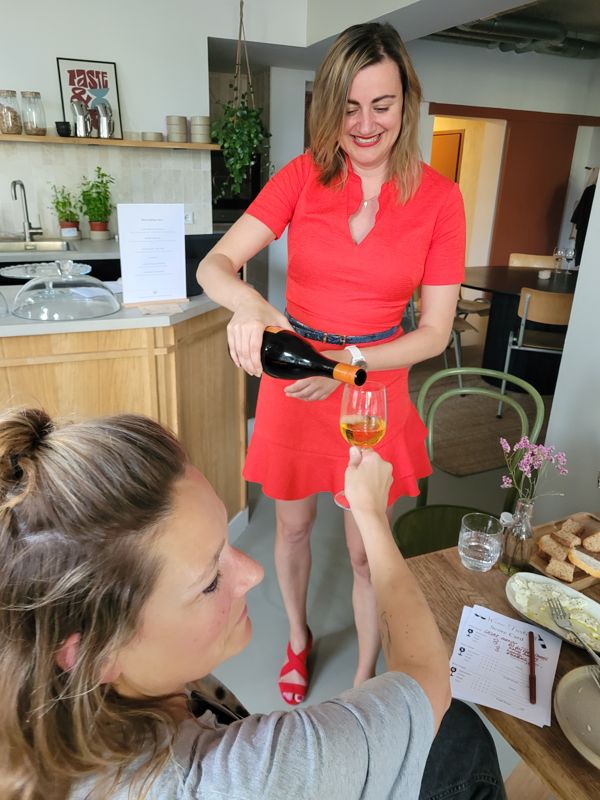 Biljana schenkt een gast een glas witte wijn in